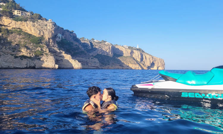 Pareja besándose frente al Cabo de la Nao junto a su moto de agua