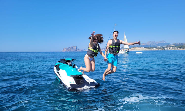 Pareja saltando al mar desde su moto de agua.