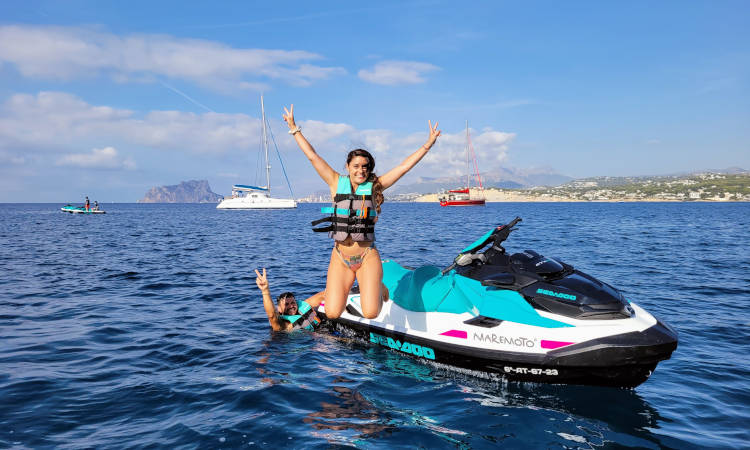 Mujer de pie en moto de agua, haciendo el signo de la paz.