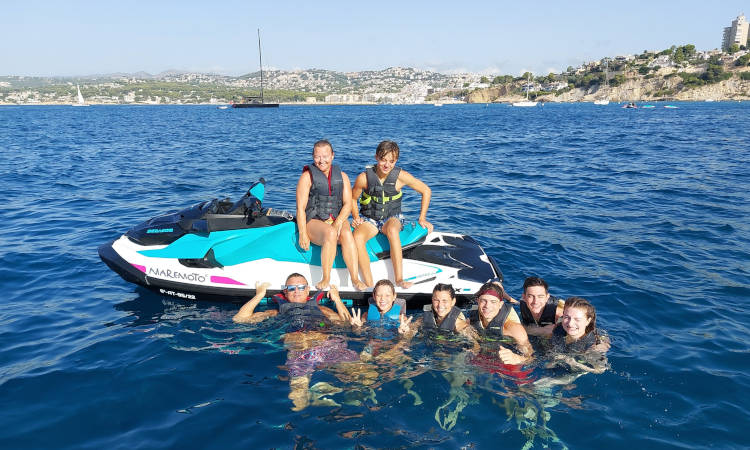 Grupo de amigos divirtiéndose en el agua cerca de su moto de agua.